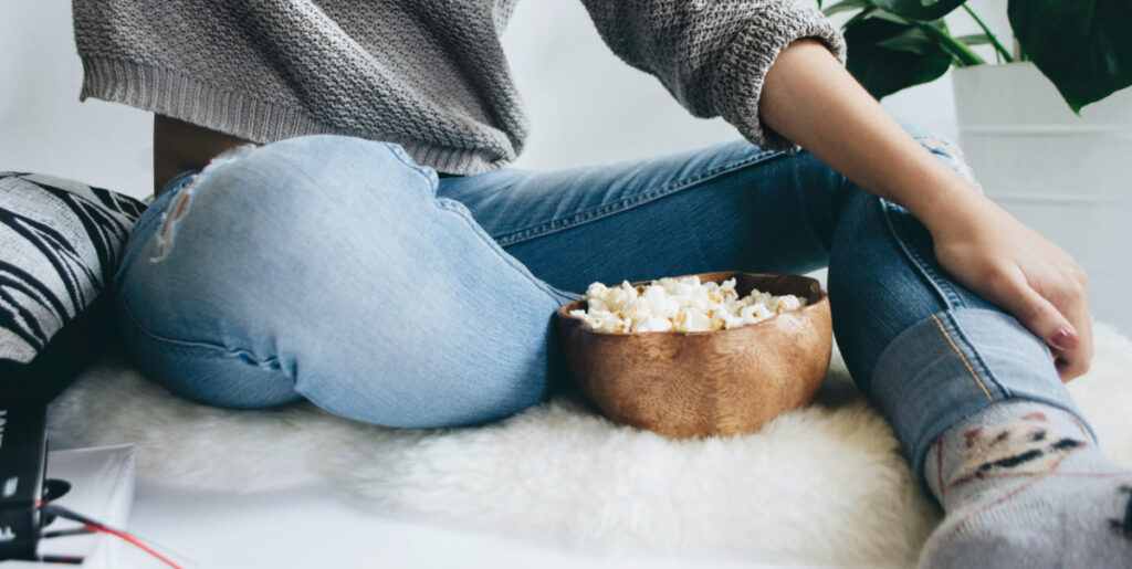 Young woman with a bowl of popcorn. Photo by Mc Jefferson Agloro on Unsplash