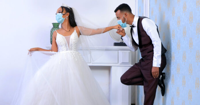 A bride and groom wearing surgical masks. Photo by mulugeta wolde on Unsplash.