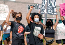 Protesters with a sign "Defund the police." Photo by Andrew Robinson on Unsplash