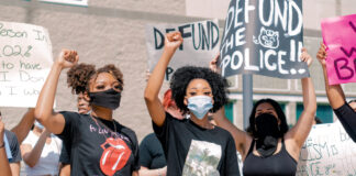 Protesters with a sign "Defund the police." Photo by Andrew Robinson on Unsplash