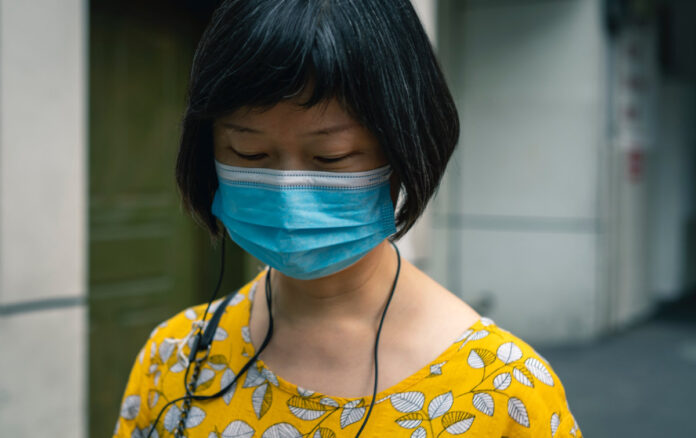 A woman wearing a face mask to reduce transmission of COVID-19. Photo by Li Lin on Unsplash.