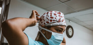 A woman wearing scrubs and a mask. Photo by SJ Objio on Unsplash