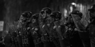 Police with riot control shields and helmets. Photo by Slaven Gujic on Unsplash