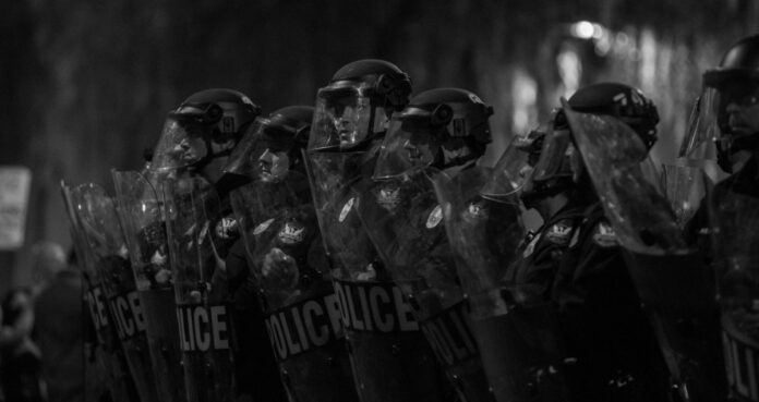 Police with riot control shields and helmets. Photo by Slaven Gujic on Unsplash