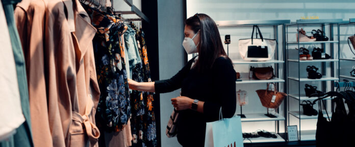 A woman shopping at a boutique hile wearing a face mask. Photo by Arturo Rey on Unsplash