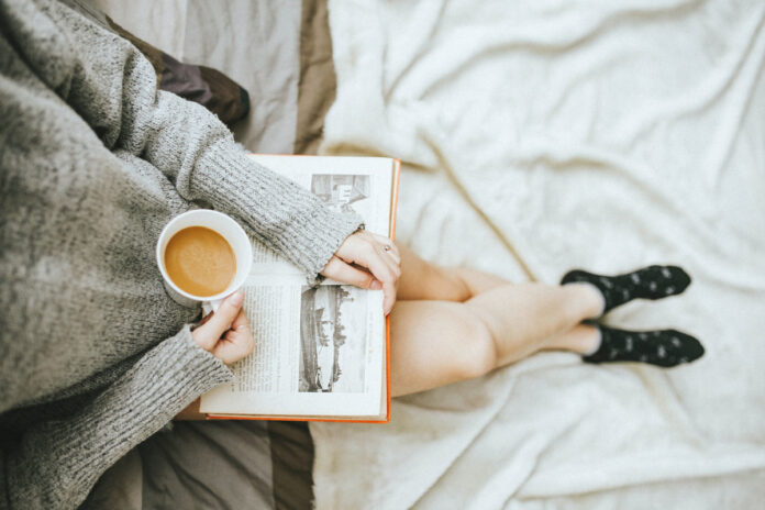 Woman reading a book and enjoying a cup of coffee. Photo by Anthony Tran on Unsplash.