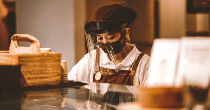 Food service employee wears a mask and shield