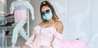 Woman in pink dress, blue mask, and sunglasses in California. Photo by kevin turcios on Unsplash.