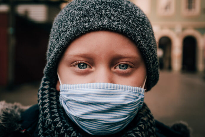 blue-eyed child in face mask and warm hat. Image by René Bittner from Pixabay.