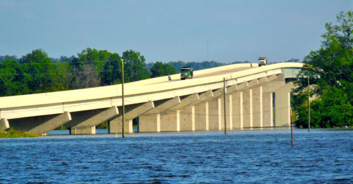 Dump trucks cross a bridge over the Mississippi River. Image by Mistyck Moon from Pixabay.