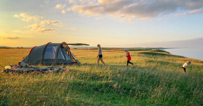 A family camping in a tent. Photo by Mattias Helge on Unsplash.