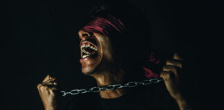 A blindfolded man in chains. Photo by Tony Rojas on Unsplash.