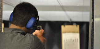 A man fires a gun at an indoor gun range