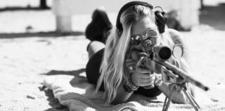 A female shooting a scoped precision rifle.