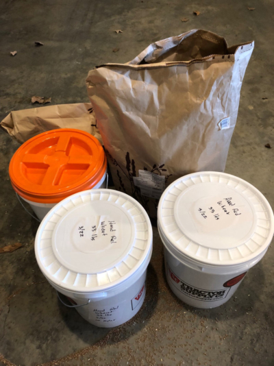 Bags of hard red wheat poured into buckets for storage