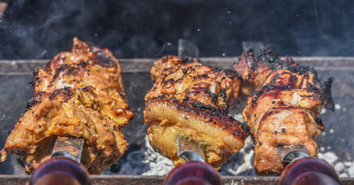 Chicken on skewers being cooked over coals