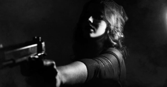 A young woman prepared to defend herself with a pistol.