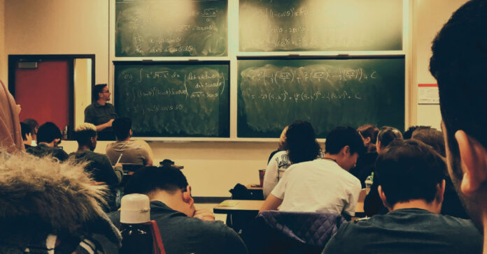 Students in a classroom with advanced equations on the board.