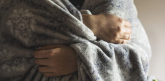A women's hands clenching a blanket.