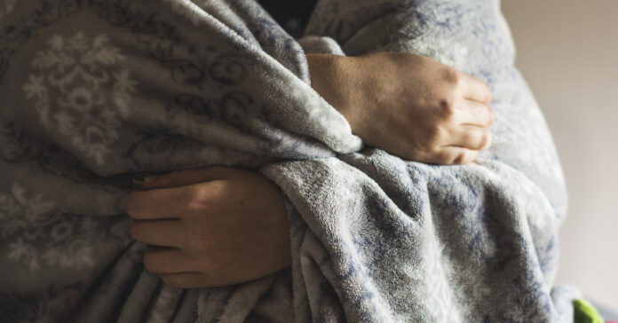 A women's hands clenching a blanket.