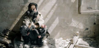 Woman in a gas mask in a destroyed building.