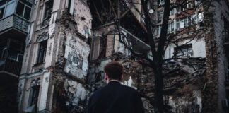 A man in front of a crumbing building in Ukraine