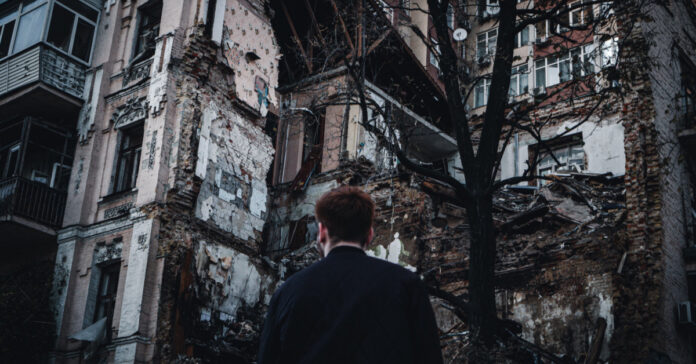 A man in front of a crumbing building in Ukraine