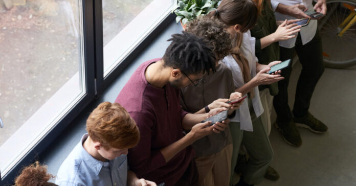 A line of people starting at their phones instead of talking to each other.