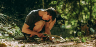 A young man using a folding saw