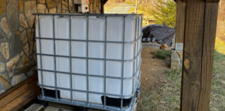 The IBC Tote positioned outside the house near our solar inverter and a woodpile. When filled with water, this will give us 275 gallons of water for firefighting.