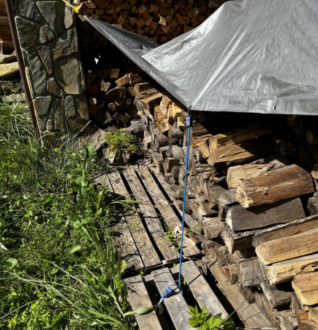 We stack our firewood on pallets to keep it from rotting on the ground and then cover it with tarps. Bungee cords help hold them in place.